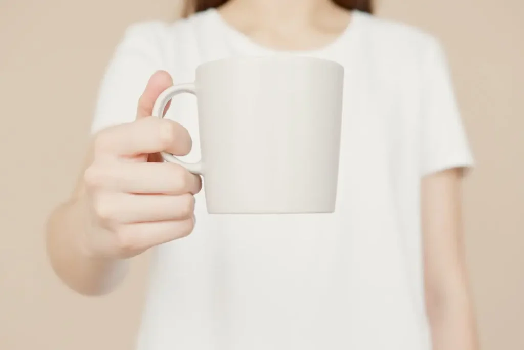 Corporate Merchandise Bundles - T-Shirt Printing KL | Custom Shirt Printing Malaysia Woman in a white t-shirt holding a blank white coffee mug, representing corporate gift sets ready for custom branding.