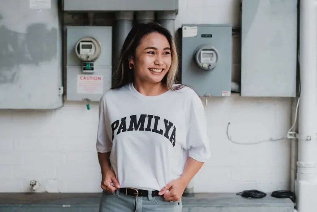 Smiling woman wearing a white custom t-shirt with sharp black arched text, demonstrating clear typography on team apparel.