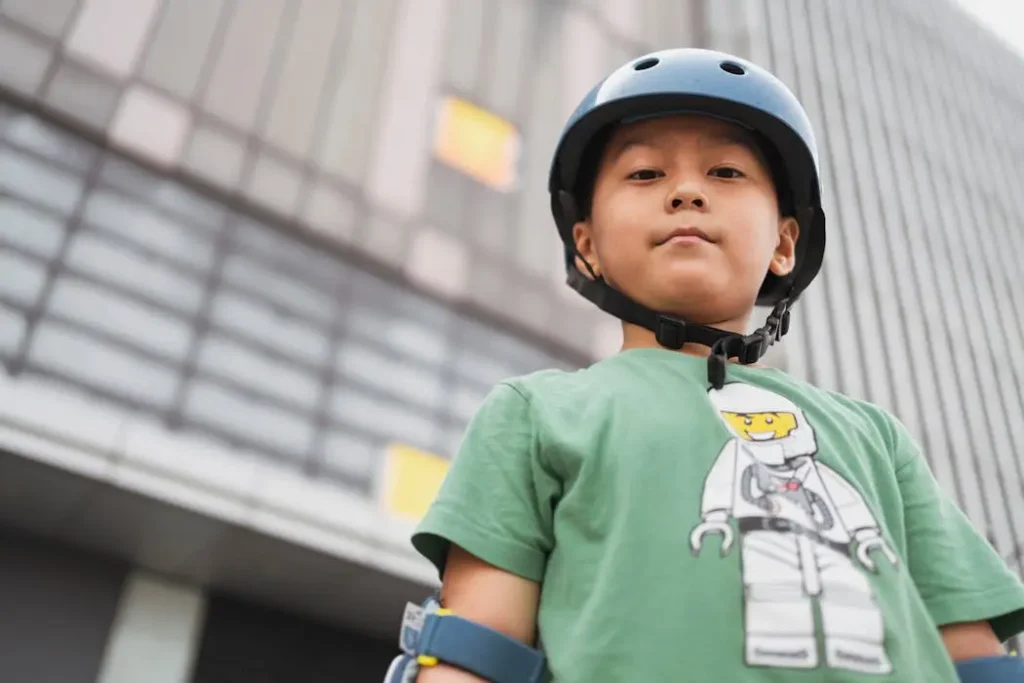Young boy wearing a green custom printed t-shirt and safety helmet, demonstrating the durability of fabric needed for active sports uniforms.