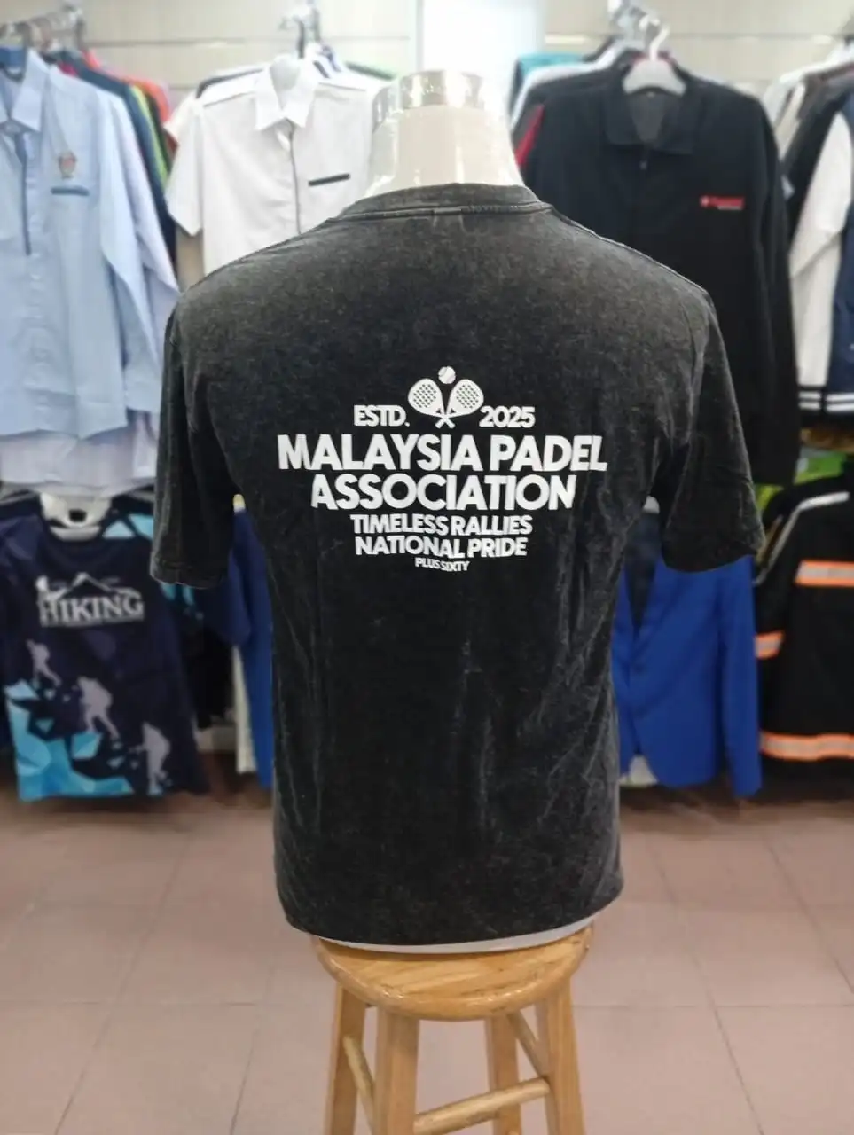 Back view of custom t-shirt showing large white'Malaysia Padel Association' typography and racket icon printed on dark vintage fabric in Kuala Lumpur.