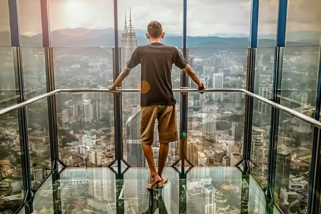 Rear view of a man looking out at the Petronas Twin Towers and Kuala Lumpur skyline, representing a local Malaysian business.