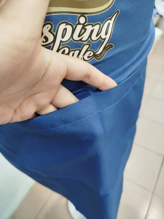 Front view of a durable blue full-bib apron featuring a large front pocket for tools, ideal for bakery or retail staff uniforms.