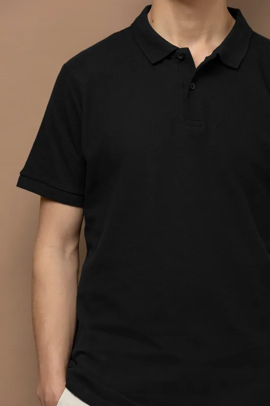 Close-up of a man wearing a plain black polo shirt with a classic collar and button placket, representing premium corporate uniform apparel.