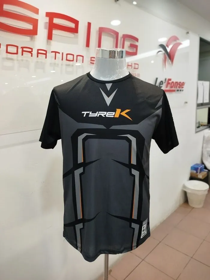 Black and grey sports jersey with complex geometric "armor" patterns and orange accents, demonstrating full sublimation printing capabilities.
