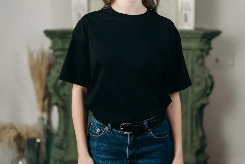 Woman wearing a fitted plain black t-shirt tucked into blue jeans, demonstrating a stylish and versatile corporate look.